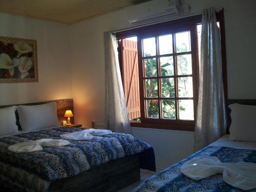 a bedroom with two beds and a window at Hospedagem Da Laranjeira Gramado in Gramado
