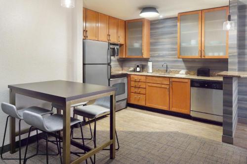 a kitchen with wooden cabinets and a table with chairs at Residence Inn by Marriott Covington Northshore in Covington