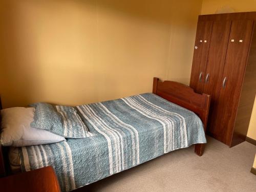 a small bedroom with a bed and a wooden cabinet at Casa Sra Oti, Tipo Hostal con vista al mar Puerto Montt - CHINQUIHUE in Puerto Montt