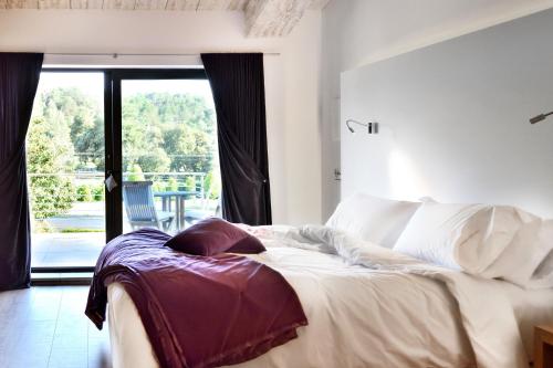 a bedroom with a bed and a large window at Boutique hotel Urbisol in Calders