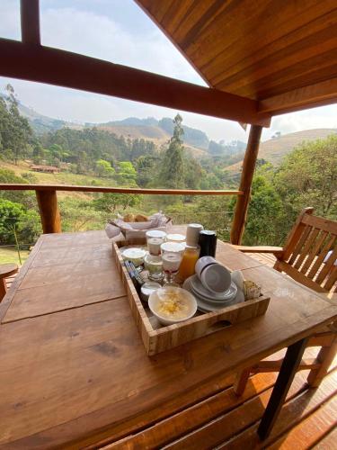 a wooden table with food on it with a view at Chalés Brisa Da Montanha in Sapucaí-Mirim