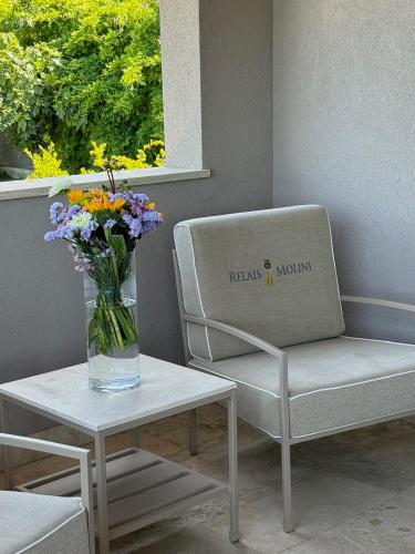 a vase of flowers sitting on a table next to a chair at Relais dei Molini - Villa dei Molini in Castagneto Carducci