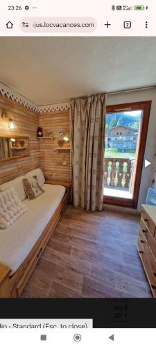 une chambre avec un lit et une grande fenêtre dans l'établissement Studio chaleureux et cosy, à Valfréjus