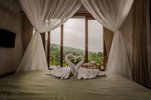 two swans towels on a bed in front of a window at Abinawa Hill in Lovina