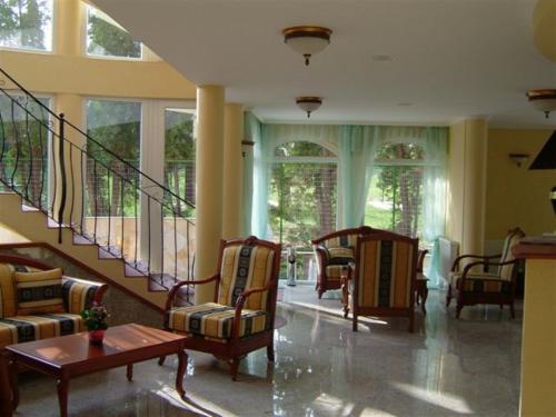 a living room with chairs and a staircase with windows at SANTE Hévíz in Hévíz