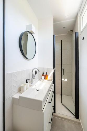 a white bathroom with a sink and a mirror at Le repaire de Barbizon in Barbizon