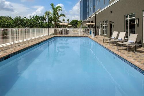 a large blue swimming pool with chairs and a building at Residence Inn Doral Mall Area in Doral