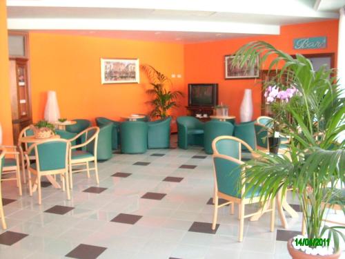 uma sala de espera com paredes e cadeiras verdes e laranja em Hotel Colorado em Lido di Jesolo