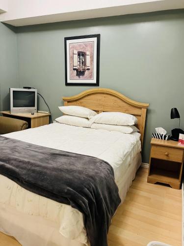 a bedroom with a large bed and a television at Saint Lawrence Residences and Suites in Toronto