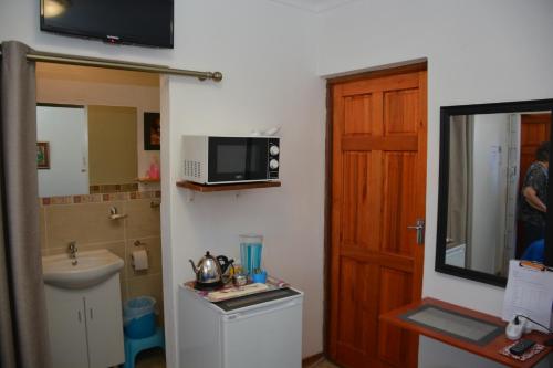 a bathroom with a sink and a microwave on the wall at Blue Crane Guest House Bloemfontein in Bloemfontein