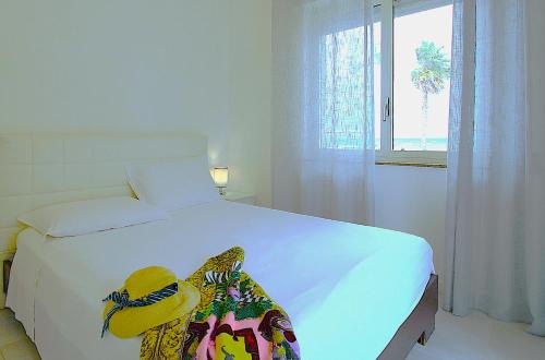 un dormitorio con una cama blanca con un sombrero amarillo encima. en Capo d'Orlando Apartments - Relax Beachside, en Capo dʼOrlando