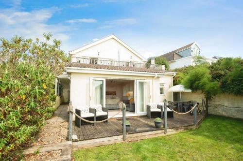 a house with a wooden deck in the yard at Stylish apartment - 2 min walk from Ogmore by sea beach with private garden, sea views & stunning sunsets, dog friendly in Tythegston
