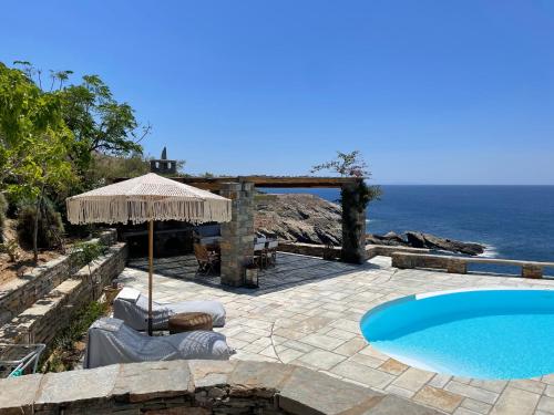 un patio con piscina, ombrellone e oceano di Waterfront Luxurious Villa - Kea Island a Melissaki