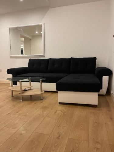 a living room with a black couch and a table at Hanwell serviced Accommodation in Greenford