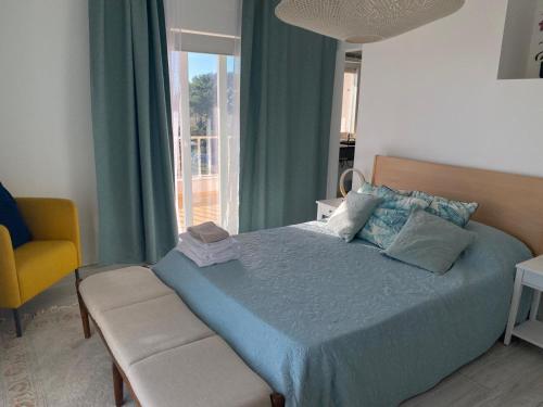 a bedroom with a blue bed and a yellow chair at Soltroia Dunas House in Troia