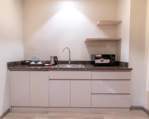 a white kitchen with a sink and a microwave at The Skye Phnom Penh Hotel & Apartments in Phnom Penh