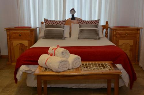 a bedroom with a bed with towels on a table at Blue Crane Guest House Bloemfontein in Bloemfontein