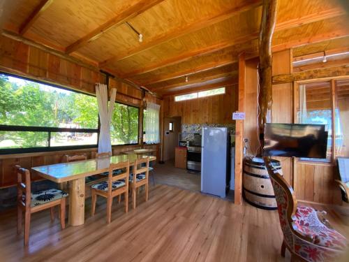 a kitchen and dining room with a table and a refrigerator at Cabaña los arrayanes full equipada con Tinaja in Valdivia