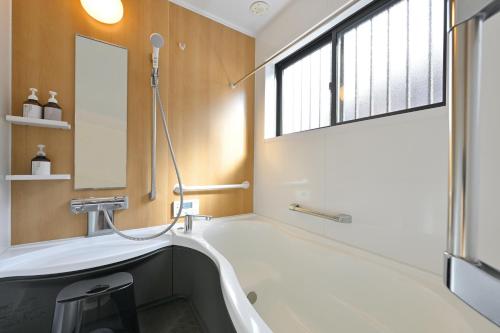 a bathroom with a tub and a sink and a window at わとなみ in Tonosho