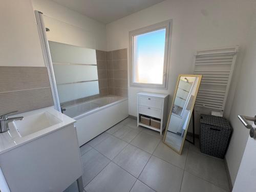 une salle de bain avec une baignoire, un lavabo et un miroir dans l'établissement Casa Nomana 4 chambres, à Saint-Jean-de-Monts