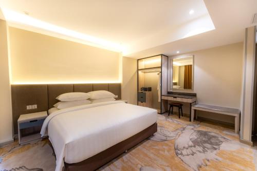 a bedroom with a large bed and a desk at The Skye Phnom Penh Hotel & Apartments in Phnom Penh