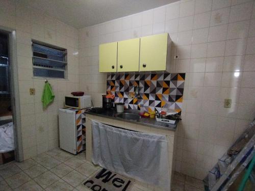 eine Küche mit gelben Schränken und einer Mikrowelle in der Unterkunft Casa na melhor localização de Santa Teresa in Rio de Janeiro