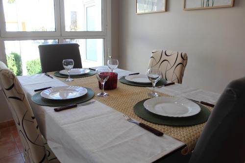 une table avec des assiettes et des verres à vin dessus dans l'établissement Apto en Cullera con terraza, piscina, parking y wifi gratis, à Cullera