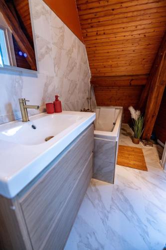 La salle de bains est pourvue d'un lavabo blanc et d'un plafond en bois. dans l'établissement Le Cocon sous les toits, à Beauvais