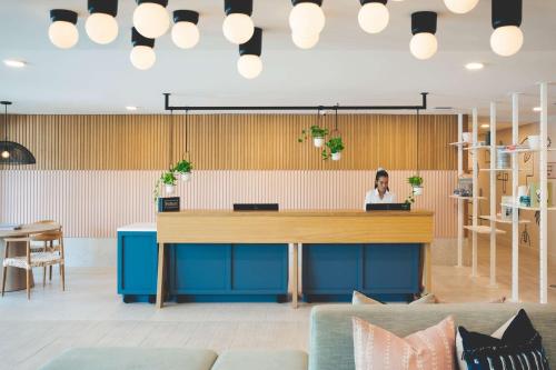 a woman sitting at a desk in an office lobby at Hampton by Hilton Grand Cayman Seven Mile Beach in George Town