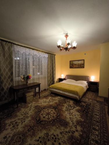 a bedroom with a bed and a table and a chandelier at Valda House in Rybie