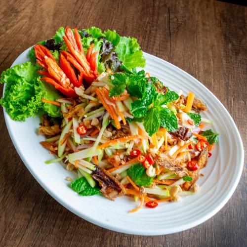 a white plate with a salad on a table at The Skye Phnom Penh Hotel & Apartments in Phnom Penh
