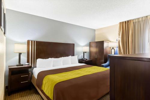 a hotel room with a bed with a yellow blanket at Sonesta Essential NW Houston in Houston