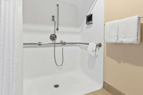 a shower stall in a bathroom with white towels at Sonesta Essential NW Houston in Houston