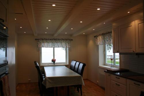 a kitchen with a table and chairs and two windows at Marisletta farm - house by the sea in Tromsø