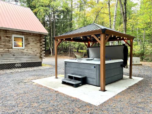 a barbecue grill under a gazebo next to a cabin at Stylish Forest Lodge with Large Hot Tub, Firepit and Fireplace minutes to Gore Mountain in North Creek