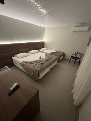 a bedroom with two beds and a table with a remote control at Hotel Pousada Villa Marina in Fortaleza