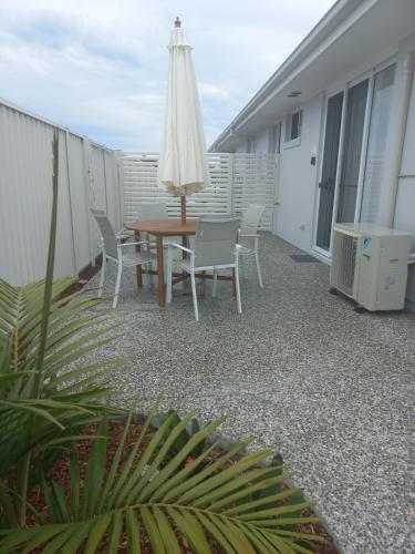 a patio with a table and chairs and an umbrella at Lillian Waters Retreat in Yamba