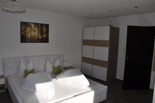 a white bed with green pillows in a room at Pension Aschlandhof in Obsteig