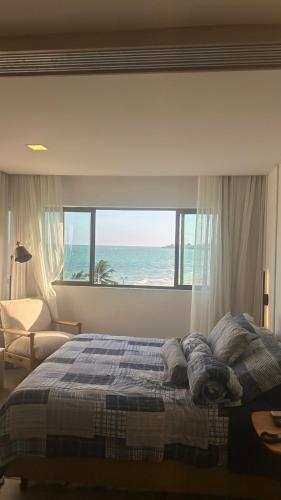 a bedroom with a bed with a view of the ocean at Flat em Hotel de Luxo beira mar da grife Ritz suítes com vista ampla para todo o mar da cruz das almas, jatiúca e ponta verde, com toda estrutura de um hotel lindo e arrojado, academia, piscina e muito mais, venha viver essa experiência incrível! in Maceió