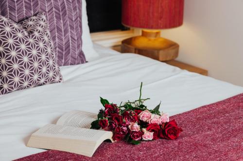 a book and a bouquet of flowers on a bed at Narrows Escape Rainforest Retreat in Montville