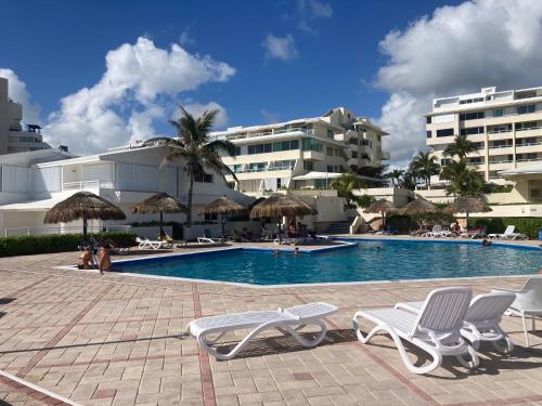 a swimming pool with chairs and umbrellas in a resort at Lagoon Sunset view entire apartment in Cancún