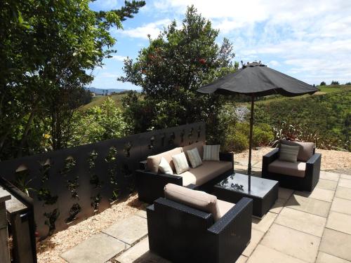 a patio with two couches and an umbrella at The Lookout- Clevedon in Clevedon