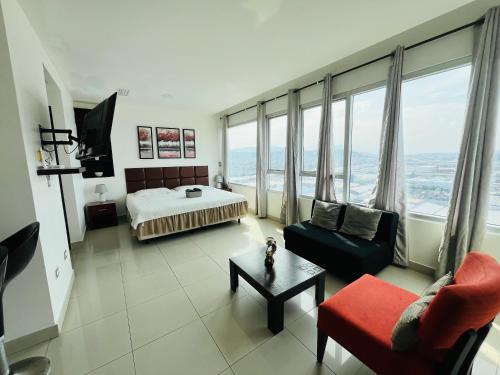 una camera da letto con un letto, un divano e una sedia di Hermosa Suite - Piscina - Gym - City Suites - 1403 a Guayaquil