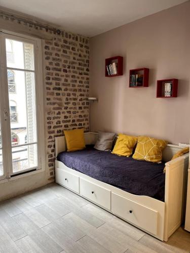 un lit dans une chambre avec un mur de briques dans l'établissement Cosy 2 Bedroom, Paris, Near Metro - 4 Peoples, à Levallois-Perret