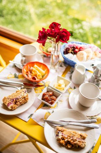 a table with plates of food and a vase of roses at Casa Rayen in Puerto Varas