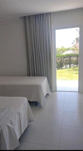 a room with two beds and a large window at Laguna verde residence in Aquiraz