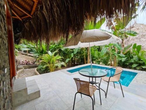 a patio with a table and chairs and an umbrella at Colibri Parque Tayrona Dentro del Parque Nacional Tayrona in El Zaino