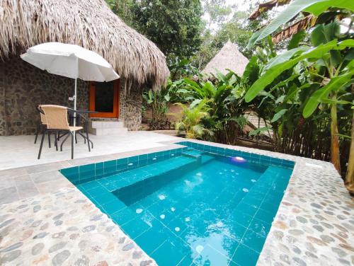 a pool with a chair and an umbrella next to a house at Colibri Parque Tayrona Dentro del Parque Nacional Tayrona in El Zaino