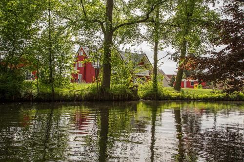 a red house sitting next to a body of water at Spreeidyll in Schlepzig