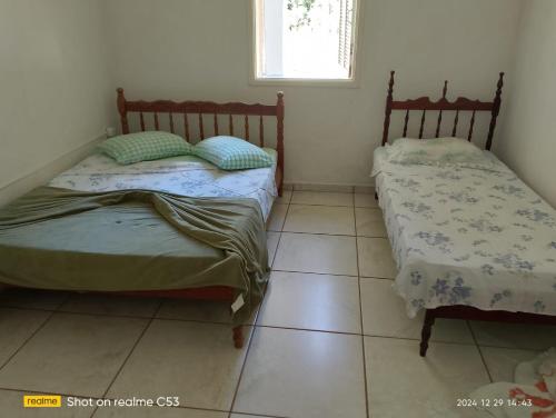 two beds in a room with a tiled floor at Pousada Sossego in São José da Barra